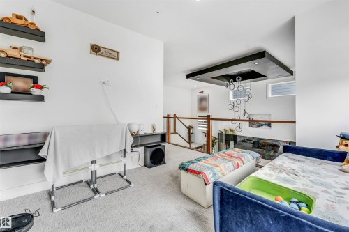 Carpeted open loft space featuring a multi-level ceiling design, recessed lighting, and a modern chandelier - 208 33 Street, Edmonton, AB 