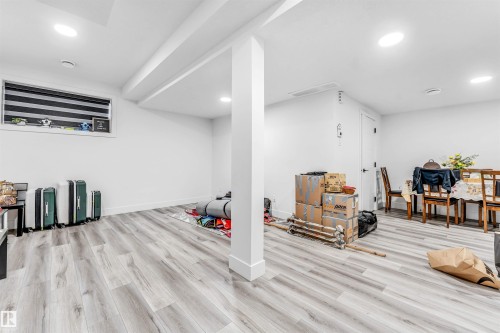 Spacious open-concept room featuring light wood-finish flooring, recessed lighting, and a white color palette - 208 33 Street, Edmonton, AB 