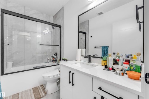 Bathroom featuring a modern vanity with white countertop, integrated sink, and matte black faucet - 208 33 Street, Edmonton, AB 