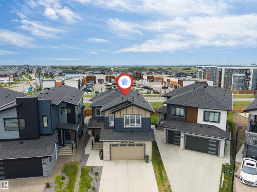 Contemporary two-story residence featuring a dark gray roof, light stone facade accents, and a two-car garage - 208 33 Street, Edmonton, AB 