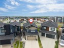 Contemporary two-story residence featuring a dark gray roof, light stone facade accents, and a two-car garage - 208 33 Street, Edmonton, AB 