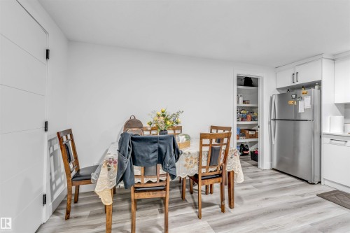 Bright dining area featuring wood-finish flooring and a contemporary white door with horizontal paneling - 208 33 Street, Edmonton, AB 
