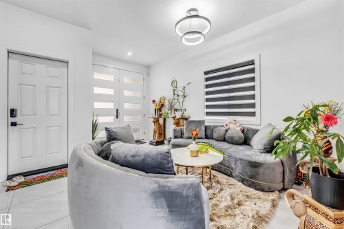 Bright entry space featuring white paneled doors, modern frosted glass double doors, a contemporary ceiling light fixture, and tile flooring - 208 33 Street, Edmonton, AB 