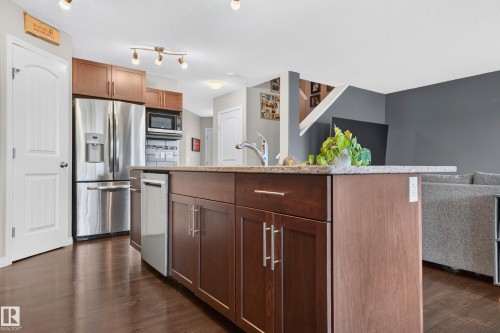 Kitchen island with granite-style countertop and dark wood-finish cabinetry - 74 Santana Crescent, Fort Saskatchewan, AB 