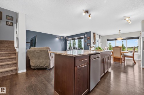 Kitchen island with dark wood-finish cabinetry, stainless steel dishwasher, and a light-toned countertop - 74 Santana Crescent, Fort Saskatchewan, AB 