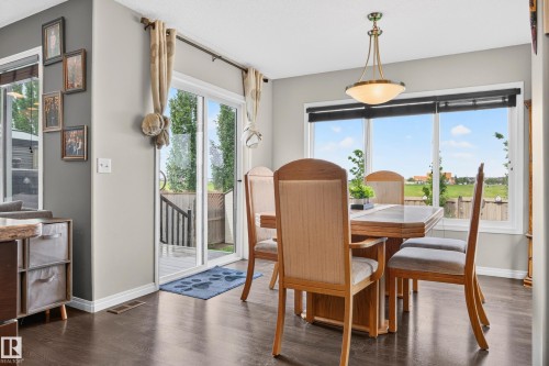 Dining area featuring dark wood-finish flooring, a large multi-pane window, and a glass sliding door - 74 Santana Crescent, Fort Saskatchewan, AB 