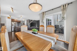 Open concept main level featuring a dining area with wood-finish flooring, a sliding glass door to the outdoor deck, and a contemporary ceiling light fixture - 
