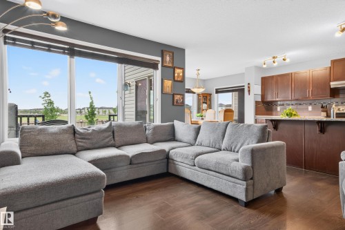 Open-concept living space featuring wood-finish flooring and large windows - 74 Santana Crescent, Fort Saskatchewan, AB 