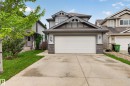 Contemporary two-story residence featuring a prominent front-facing double garage, stone column accents, and gabled rooflines - 74 Santana Crescent, Fort Saskatchewan, AB 