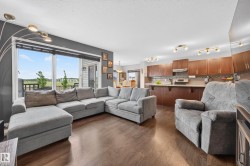 Open-concept living area featuring wood-finish flooring and a kitchen with warm wood cabinetry - 