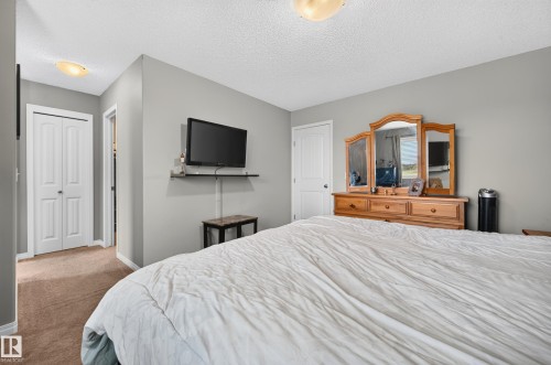 Bedroom featuring light gray walls, textured white ceiling, and light brown carpeting - 74 Santana Crescent, Fort Saskatchewan, AB 