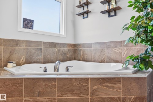 Built-in soaking tub featuring chrome fixtures, surrounded by large format natural stone-look tile - 74 Santana Crescent, Fort Saskatchewan, AB 