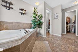 Oversized soaking tub with tiled surround and chrome fixtures - 