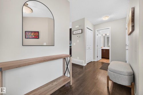 Entryway featuring dark wood-finish flooring, a contemporary arched mirror, and light gray wall paint - 74 Santana Crescent, Fort Saskatchewan, AB 