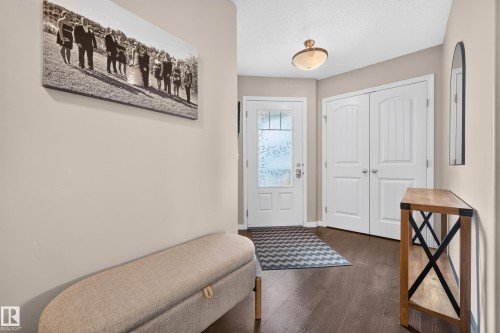 Entryway featuring dark wood-finish flooring, a white front door with decorative frosted glass, and double white paneled doors - 74 Santana Crescent, Fort Saskatchewan, AB 
