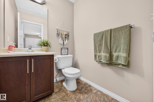 Bathroom featuring a dark wood-finish vanity with a light countertop, undersink storage, chrome fixtures, and a wall-mounted mirror - 74 Santana Crescent, Fort Saskatchewan, AB 