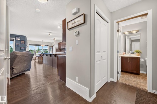 Hardwood-style flooring extends through the entryway, opening to a spacious living area with ample natural light - 74 Santana Crescent, Fort Saskatchewan, AB 