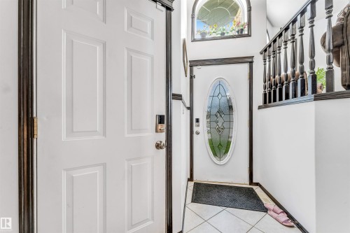 Entryway featuring a decorative glass door, tiled flooring, and an arched window above - 6719 164 Ave, Edmonton, AB 