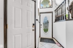 Entryway featuring a decorative glass door, tiled flooring, and an arched window above - 