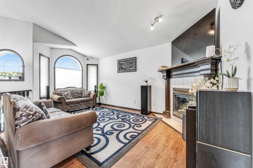Living area featuring wood-finish flooring, a fireplace with a decorative mantel, and arched windows - 6719 164 Ave, Edmonton, AB 