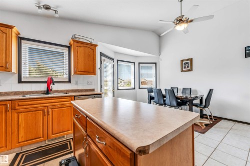 Kitchen featuring wood cabinetry, a center island with a light-toned countertop, and an integrated dining area with a bay window - 6719 164 Ave, Edmonton, AB 