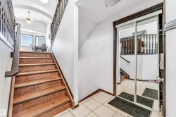 Entryway featuring a wood-finish staircase with dark wood railings, leading to a vaulted ceiling with an overhead light fixture - 