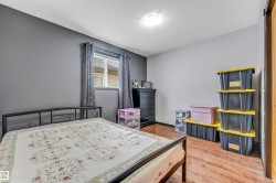 Bedroom featuring wood-finish flooring, a window with blinds, and a built-in overhead light fixture - 
