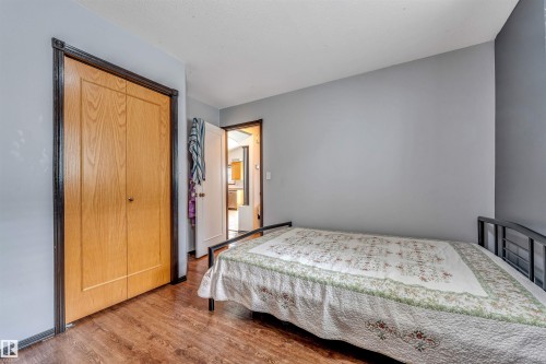 Room featuring wood-finish flooring, light grey painted walls, and a closet with bifold wood doors and dark trim - 6719 164 Ave, Edmonton, AB 