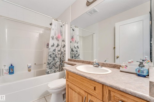 Full bathroom featuring a single vanity with wood-finish cabinetry, a neutral countertop, and an integrated sink - 6719 164 Ave, Edmonton, AB 