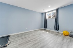 Spacious room featuring light blue walls, wood-finish flooring, recessed lighting, and a window with white trim - 