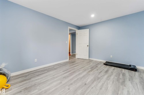 Spacious room featuring light blue walls and wood-finish flooring - 6719 164 Ave, Edmonton, AB 