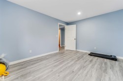 Spacious room featuring light blue walls and wood-finish flooring - 