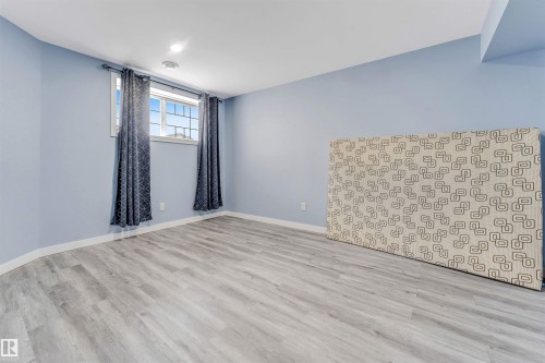 Spacious room featuring light blue walls, wood-finish flooring, and white trim - 6719 164 Ave, Edmonton, AB 