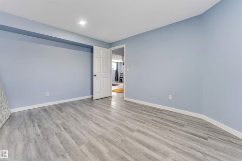 Spacious room featuring light blue walls, recessed lighting, and wood-finish flooring - 6719 164 Ave, Edmonton, AB 