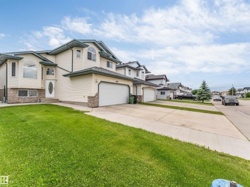 Two-story property featuring light-colored siding, a dark-colored roof, and a prominent arched window on the facade - 6719 164 Ave, Edmonton, AB 