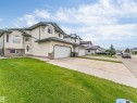 Two-story property featuring light-colored siding, a dark-colored roof, and a prominent arched window on the facade - 6719 164 Ave, Edmonton, AB 