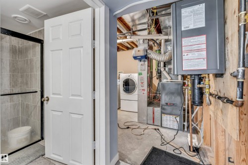 Utility area featuring a tankless water heater, furnace system, and washer and dryer units - 6719 164 Ave, Edmonton, AB 