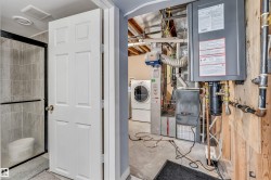 Utility area featuring a tankless water heater, furnace system, and washer and dryer units - 