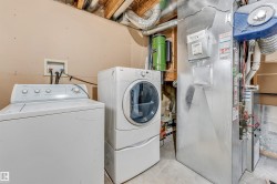 Dedicated utility area featuring a top-load washer, front-load dryer with pedestal, furnace, and exposed ceiling joists - 