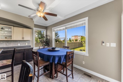 Eat-in kitchen area featuring a coffered ceiling with a ceiling fan, tiled flooring, and multiple windows - 488 Macewan Road, Edmonton, AB 