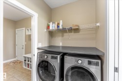 Dedicated laundry area featuring a dark countertop, upper wire shelving, and two front-loading appliances - 