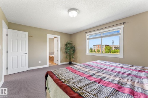Spacious bedroom featuring neutral wall paint, white trim, and a window offering natural light - 488 Macewan Road, Edmonton, AB 