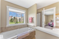 Jetted soaking tub with tile surround, framed by a large window with natural light - 