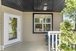 Covered porch entry featuring a full-light door, horizontal siding, and a dark-stained wood ceiling with an exterior light fixture - 