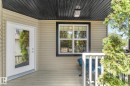 Covered porch entry featuring a full-light door, horizontal siding, and a dark-stained wood ceiling with an exterior light fixture - 488 Macewan Road, Edmonton, AB 
