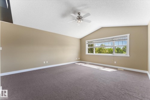Room featuring a vaulted ceiling with a ceiling fan, a large window with blinds, and neutral-toned carpeting - 488 Macewan Road, Edmonton, AB 