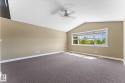Room featuring a vaulted ceiling with a ceiling fan, a large window with blinds, and neutral-toned carpeting - 