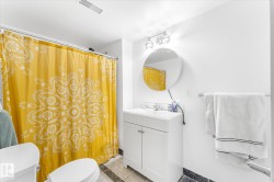 Full bathroom featuring a white vanity with integrated sink, chrome hardware, a round wall-mounted mirror, and tile flooring - 