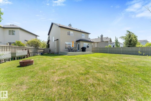 Expansive rear yard featuring a large green space, a multi-level wood deck, and a fire pit - 488 Macewan Road, Edmonton, AB 