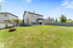 Expansive rear yard featuring a large green space, a multi-level wood deck, and a fire pit - 